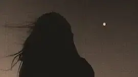 Silhouette of a woman watching the moon under a moonlit sky