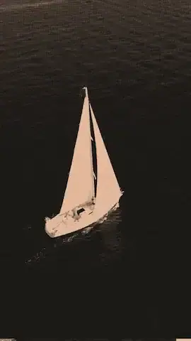 A sailing yacht navigating calm waters at sunset