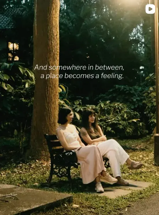 Two women sitting on a bench among trees, with the words: And somewhere in between, a place becomes a feeling.
