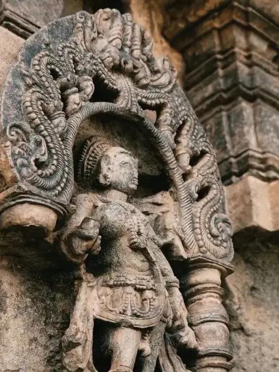 A carved stone figure beneath an ornate arch on a temple wall