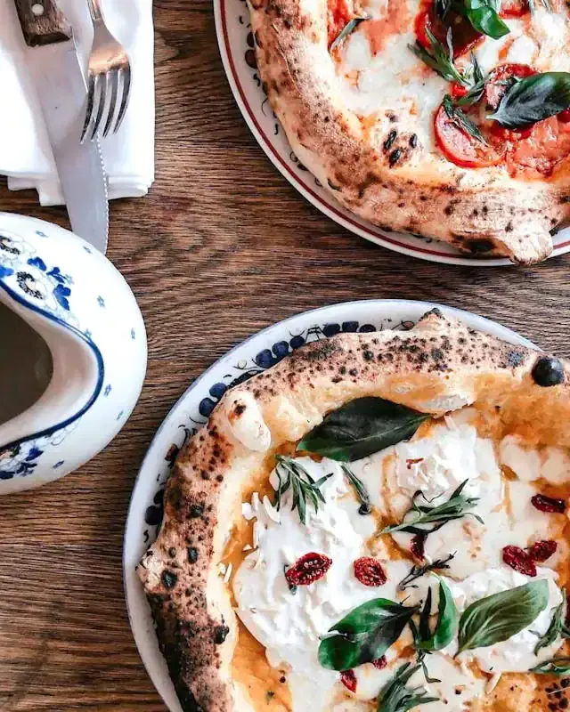 Delicious Neapolitan pizza with basil, cherry tomatoes, and mozzarella cheese on a wooden table.