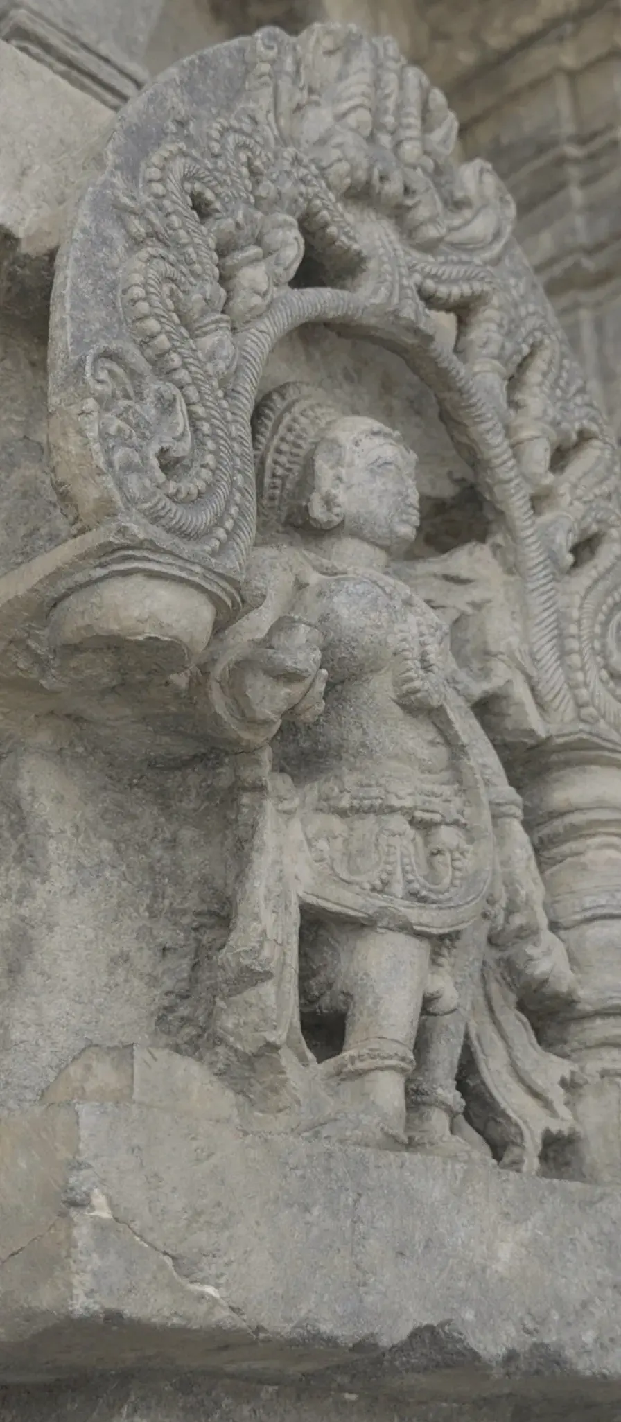 Carved stone figures in arched niches along an old temple wall