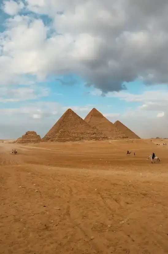 Ancient Great Pyramid of Giza in Egypt with desert landscape and cloudy sky.